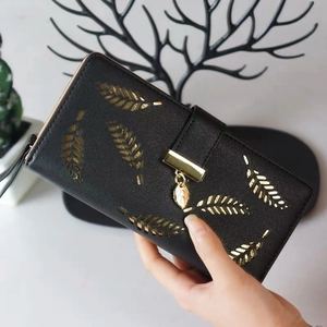 Detail of elegant black PU leather wallet with gold leaf pendant and embossed hollow patterns