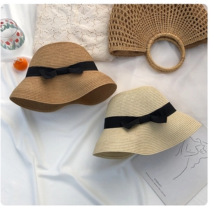 Flat lay of khaki and cream straw sun hats with black bows and a matching handbag