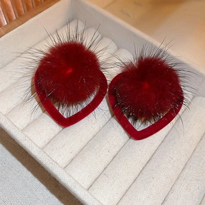 Close-up of red heart-shaped earrings with soft plush fur texture on a jewelry box
