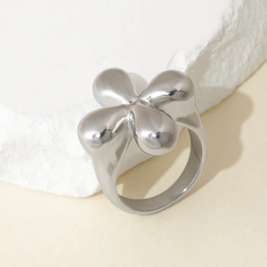 Macro shot of silver titanium steel ring with a polished puffed four-leaf flower design