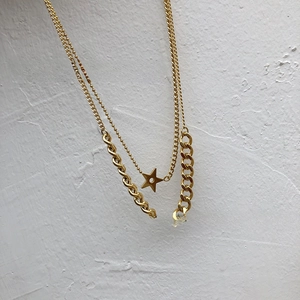 Close-up of gold double-layer necklace featuring a star pendant and thick curb chain