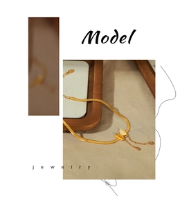 Detail of gold-plated butterfly charm with tassels and round beads on a snake chain