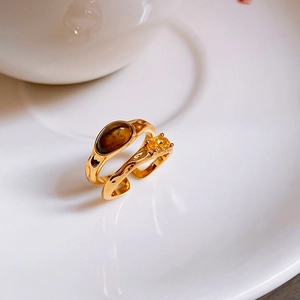 Detail of gold-plated open ring featuring oval tiger eye stone and faceted zircon