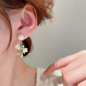Détail des boucles d'oreilles muguet avec fleurs en émail blanc et perles