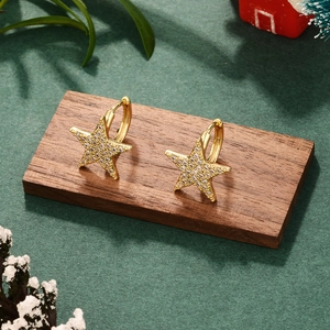 Detailed close-up of gold star moon earrings with pavé crystals on a festive background