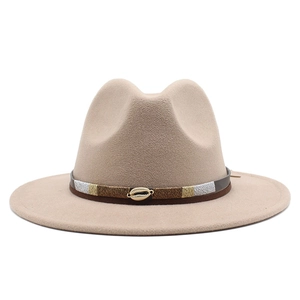 Detail of khaki fedora hat featuring a brown leather band and metallic shell ornament