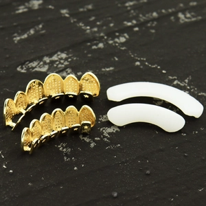 Close-up of golden hollow hiphop grillz set with white silicone molding bars