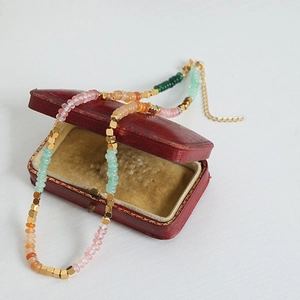 Detail of colorful beads and gold spacers on a Bohemian necklace over a jewelry box