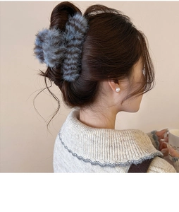 Detail of plush grey-blue faux fur claw clip on hair bun worn with knit sweater