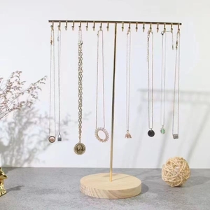 Golden T-bar metal jewelry stand with wooden base displaying multiple necklaces