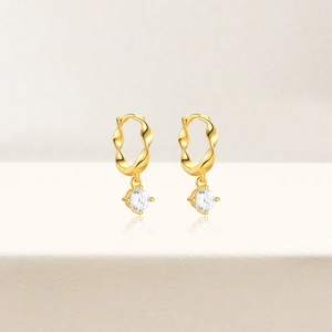 Close-up of gold star earrings with sparkling cubic zirconia on wavy metal hoops