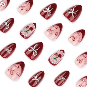 Almond-shaped press-on nails featuring burgundy red tips with 3D bows and cherry designs