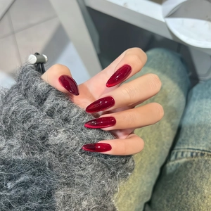 Faux ongles œil de chat longs amande rouge bordeaux portés sur la main