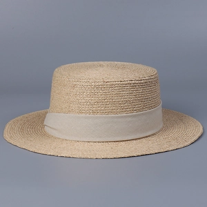 Gros plan sur un chapeau canotier en raphia naturel avec ruban crème et texture tissée
