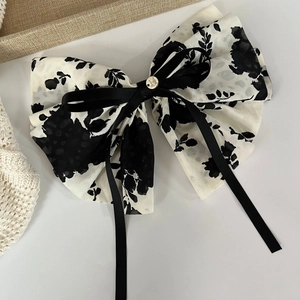 Detail of floral chiffon bow hair tie with black ribbon and gold button accent