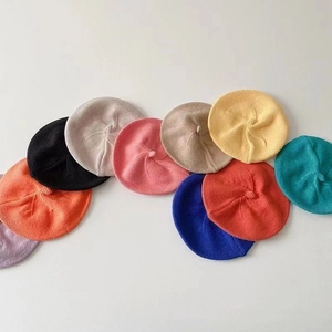 Détail à plat montrant dix couleurs vives de bérets en tricot pour bébés et enfants