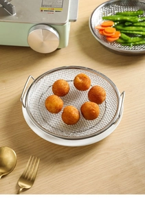 Close-up of stainless steel frying basket with golden fried snacks and dual handles