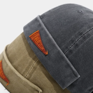 Gros plan de bonnets docker vintage avec étiquettes en cuir orange et texture en sergé de coton