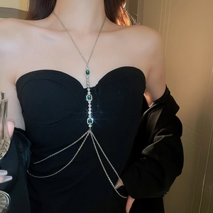 Détail de la chaîne de corps argentée avec cristaux vert émeraude sur robe noire