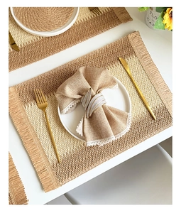 Close-up of rectangular woven jute placemats with fringe edge and gradient beige tones