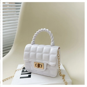 Detailed view of white quilted jelly handbag with golden lock and chain on white books