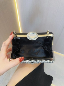 Detail van zwarte satijnen avondclutch met strassranden en een kristallen sluiting