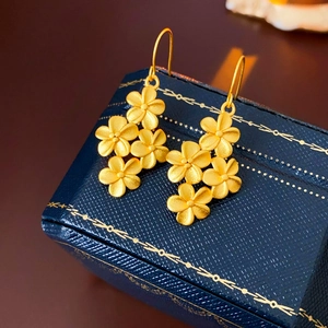 Vue macro de boucles d'oreilles fleur plaquées or 18K sur un coffret bleu marine