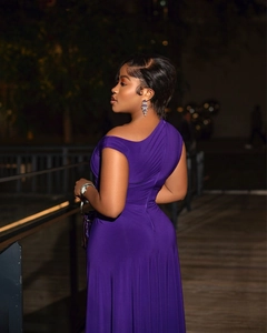 Detail of elegant deep purple one-shoulder evening dress with ruched waist and slit