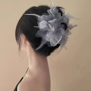 Detailed back view of a grey rose feather hair claw clip on model's braided hair