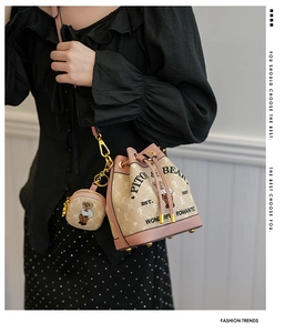 Detail of pink and beige drawstring bucket bag with bear motif and mini round pouch charm
