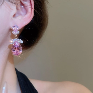 Gros plan sur des boucles d'oreilles goutte en zircon rose avec monture dorée