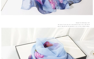 Detail of light blue floral silk scarf showing delicate printed flowers and hemmed edges