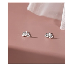 Macro shot of silver lotus stud earrings with elegant matte texture on pink surface