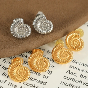 Macro shot of gold and silver conch shell earrings on a vintage paper background