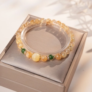 Détail macro d'un bracelet en cristal jaune ambré avec touches vertes en boîte cadeau luxe