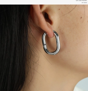 Detailed view of silver U-shaped hoop earrings on a model showing polished metallic texture