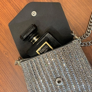 Detail of mini rhinestone crossbody bag with silver chain and magnetic closure