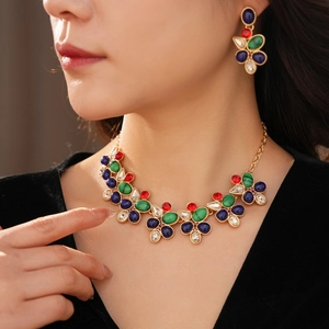 Nahaufnahme eines Vintage-Schmucksets aus Gold mit bunten Edelsteinen an einem Model