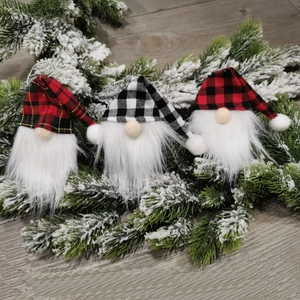 Three-piece Nordic Christmas gnome set with plaid hats on snow-covered pine needles