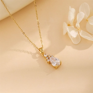 Elegant gold drop pendant necklace featuring a teardrop zircon stone on warm beige backdrop
