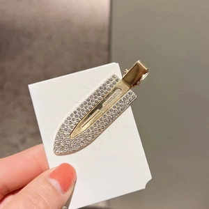 Detail of a gold-plated rhinestone hair clip with hand showing craftsmanship on card