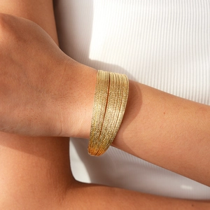 Detailed macro view of multi-layered gold wire bracelet with elegant glitter texture
