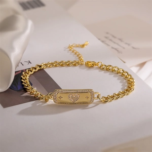 Detailed macro shot of golden Cuban chain bracelet with heart-shaped cubic zirconia charm