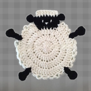 Detailed view of handmade crochet sheep coaster with black and white knit texture