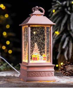 Close-up of a pink Christmas lantern featuring a snowy tree and gifts with a bokeh background