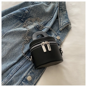 Vue de dessus d'un sac cylindrique en cuir PU noir avec chaîne argentée sur veste en jean