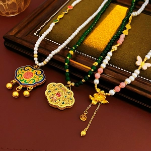 Detailansicht von Vintage-Goldketten mit Lotus-Anhängern und bunten Perlen auf Holz
