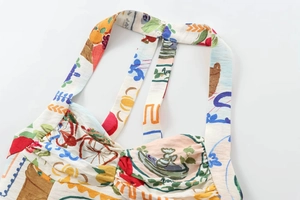 Close-up of halter neck dress with artistic fruit and plant prints on linen fabric