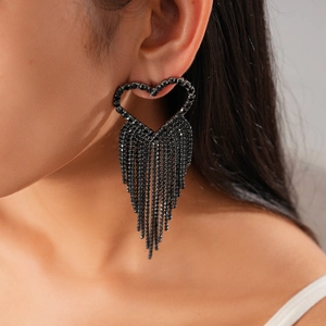 Close-up of black rhinestone heart earrings with long fringe on a model wearing dark fashion