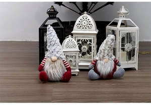 Close-up of plush Christmas gnomes with striped sleeves and long beards on wood floor